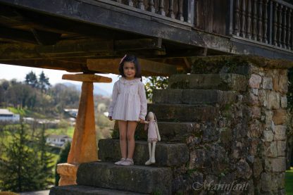 Niña posando en horreo asturiano con jesusito rayas arena y rosa.